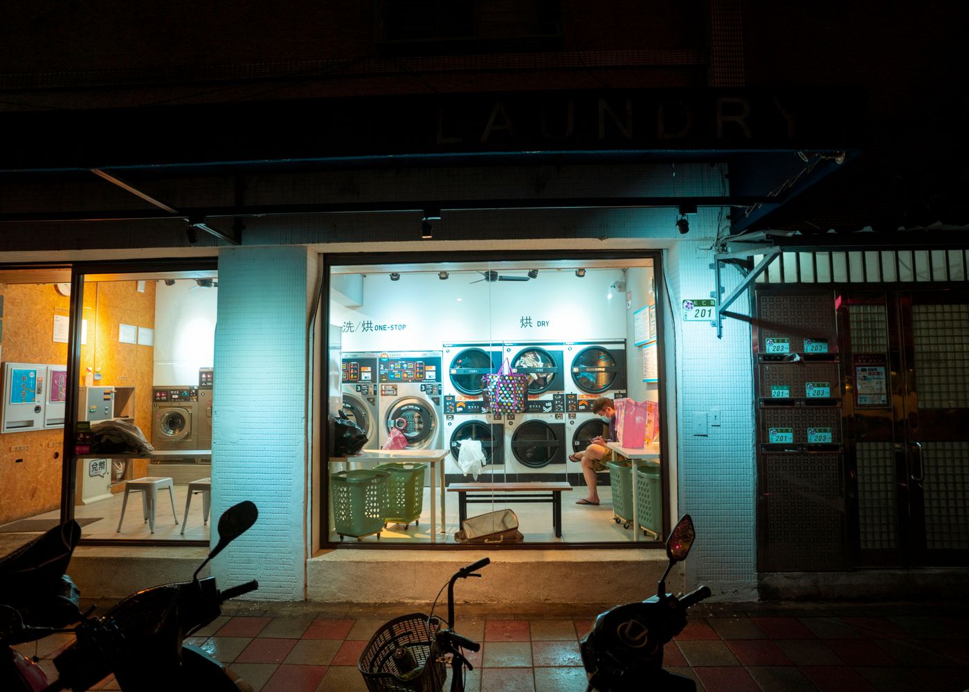 A warm, modern New York laundromat at night